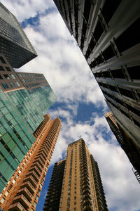 Low angle view of modern buildings against cloudy sky in city