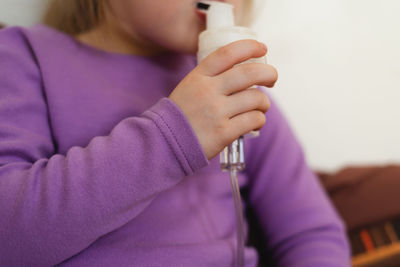 Child lies in bed and makes inhalation using a nebulizer.close-up of a child's hand with a nebulizer