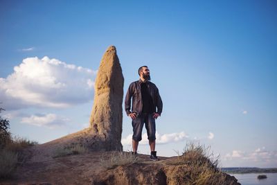 Brutal man with a beard on the background of the sky and mountains
