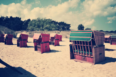 Hooded chairs on beach against sky