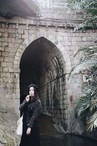 Woman eating lollipop while standing against arch