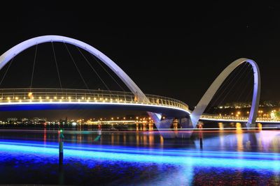 Illuminated bridge over river at night