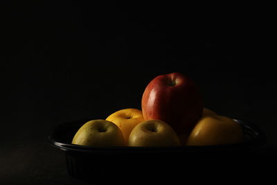 Close-up of fruits in bowl against black background