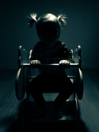 Girl sitting on rocking chair in darkroom at home