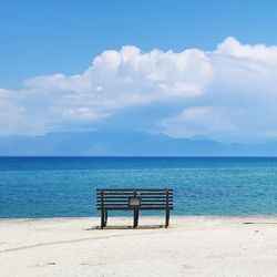 Empty deck chairs on beach against blue sky