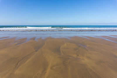 Scenic view of beach against clear blue sky