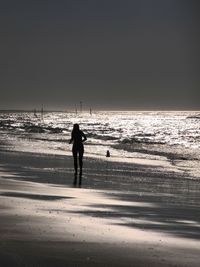 Silhouette man walking on beach against clear sky