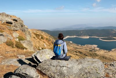 Rear view of young woman sitting on rock