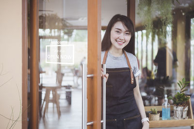 Portrait of smiling young woman standing in corridor