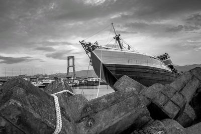 Abandoned boat on rocks against sky