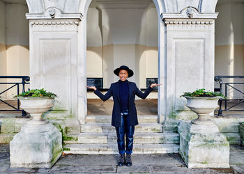 Full length portrait of young man standing against building