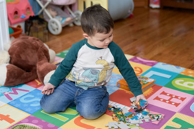 Cute little boy playing with toys and puzzles in his room