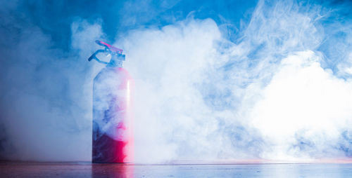 A fire extinguisher stands in the smoke of a fire
