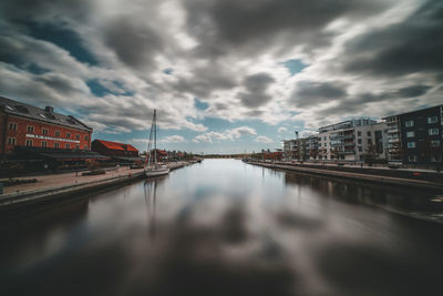 Reflection of buildings in river against sky in city