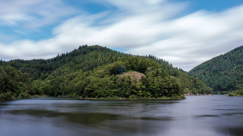 Scenic view of river amidst trees against sky