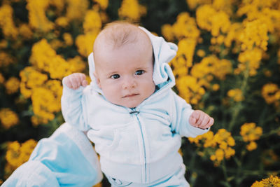 Close-up of cute baby boy against yellow flowering plants