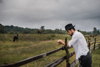 Man standing by fence on field
