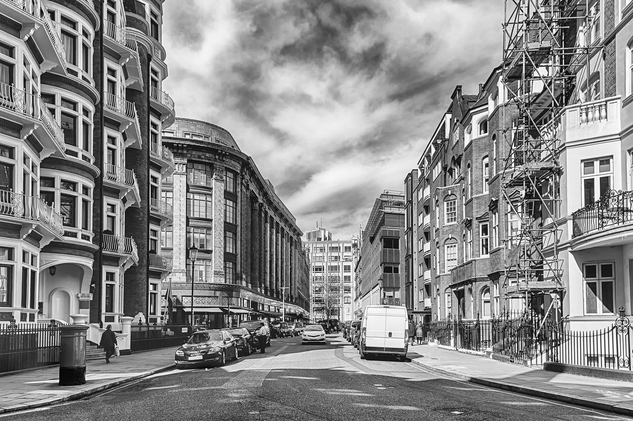 architecture, building exterior, road, built structure, city, street, black and white, cityscape, sky, transportation, infrastructure, cloud, building, monochrome, monochrome photography, urban area, metropolis, mode of transportation, car, neighbourhood, motor vehicle, nature, city street, residential area, residential district, day, lane, city life, travel destinations, no people, town, outdoors, the way forward, sign, travel, house, land vehicle, vehicle, symbol, alley