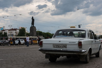 Cars on road against cloudy sky