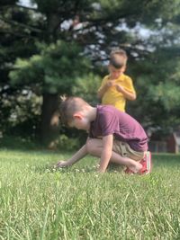 Rear view of siblings playing on grass