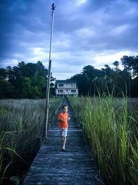 People walking on road against cloudy sky