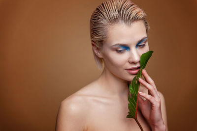 Portrait of young woman with make-up against wall