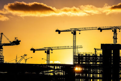 Silhouette of construction site against sky during sunset