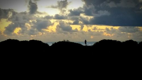 Silhouette landscape against cloudy sky