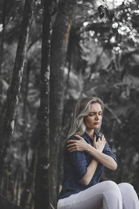 Young woman sitting on tree trunk in forest