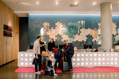 Family looking at man talking to receptionist in hotel