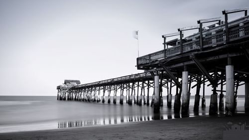 Low angle view of pier over sea against clear sky