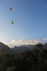 Hot air balloons flying in mountains against sky