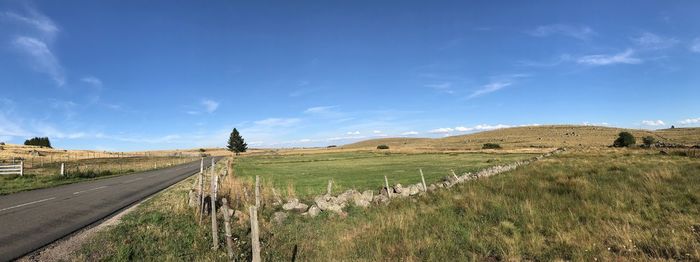 Empty road amidst field against sky