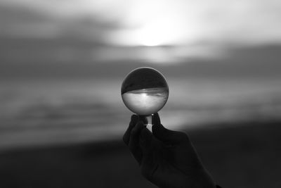 Person holding crystal ball against sky