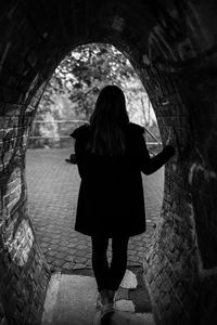 Rear view of woman standing in tunnel