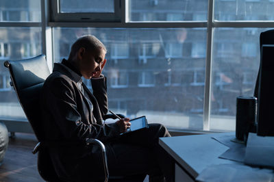 Young man using mobile phone while sitting on chair