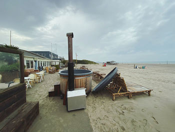 Deck chairs on beach against sky