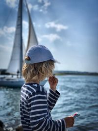 Rear view of boy in sea against sky