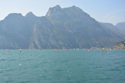 People in sea against mountain and sky