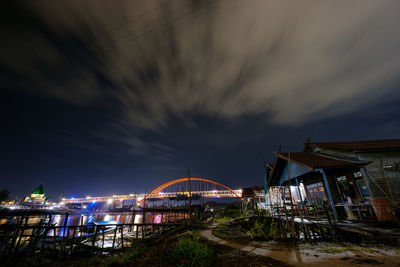 Illuminated bridge over river against sky at night