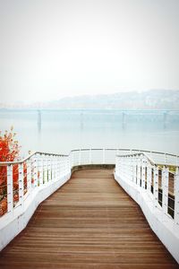 Wooden boardwalk leading towards sea against sky