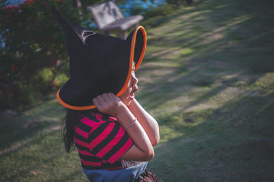 Side view of girl wearing witch hat on field