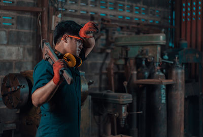 Man holding equipment while working in factory