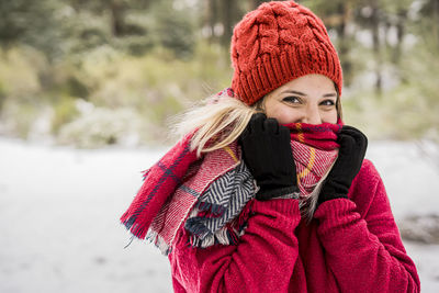 Portrait of young woman in red knit hat standing outdoors during winter