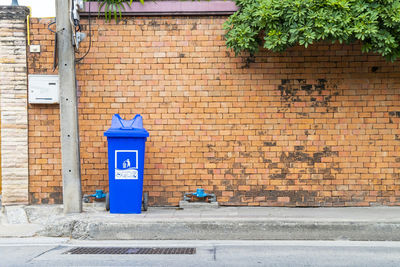 Garbage bin against brick wall