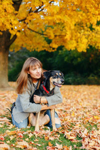 Woman embracing dog while kneeling at park