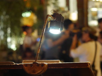 Close-up of man photographing illuminated lamp