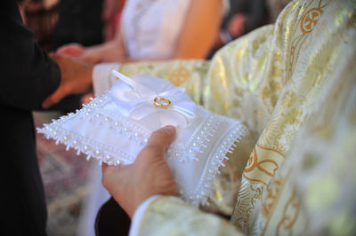 Midsection of priest holding wedding ring while standing by couple