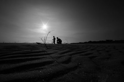 Silhouette people on field against sky during sunset