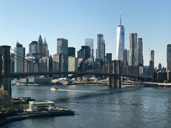 Brooklyn bridge and east river against sky in city